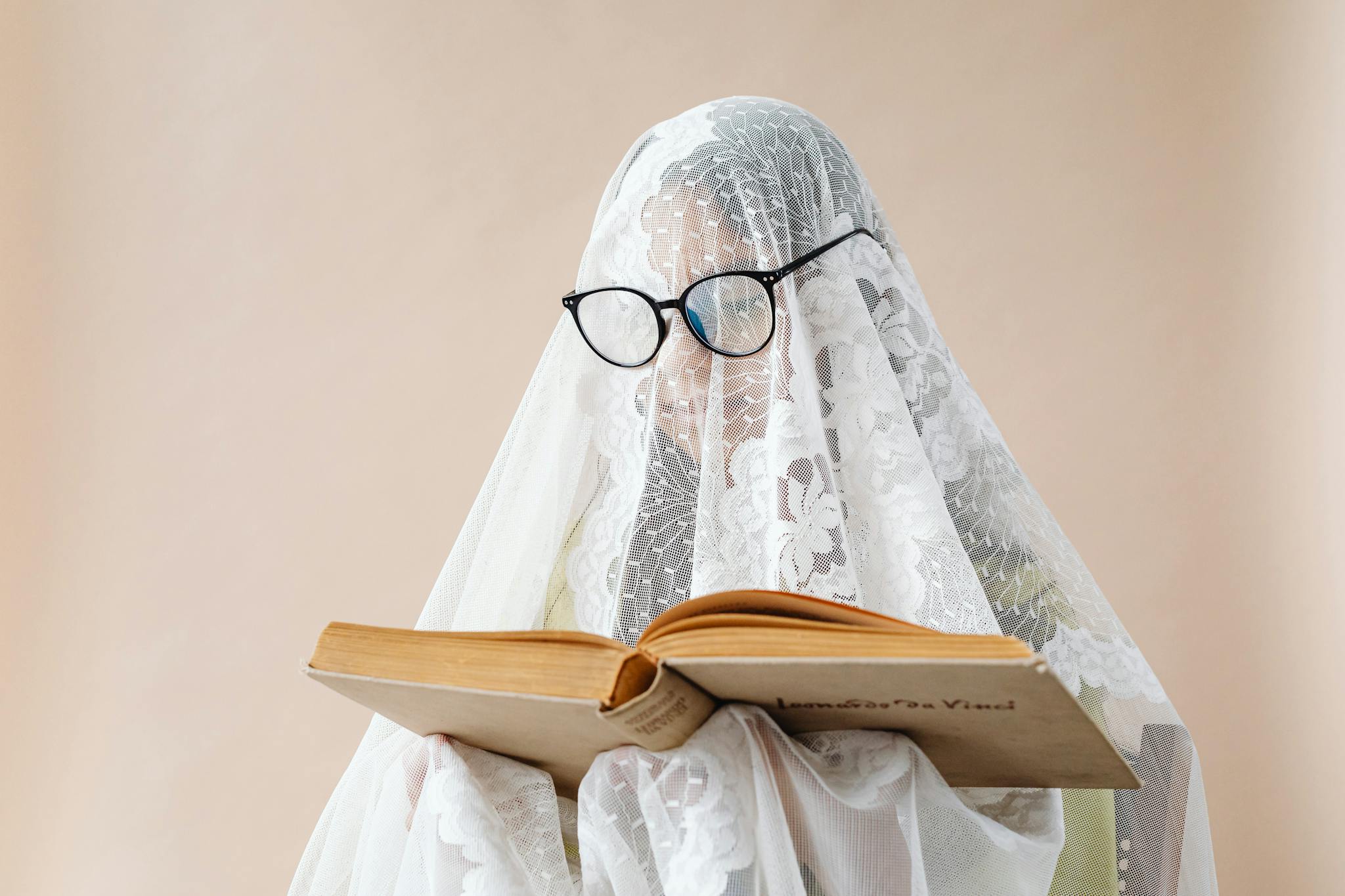 A whimsical scene featuring a person under a lace veil reading a book, wearing glasses.